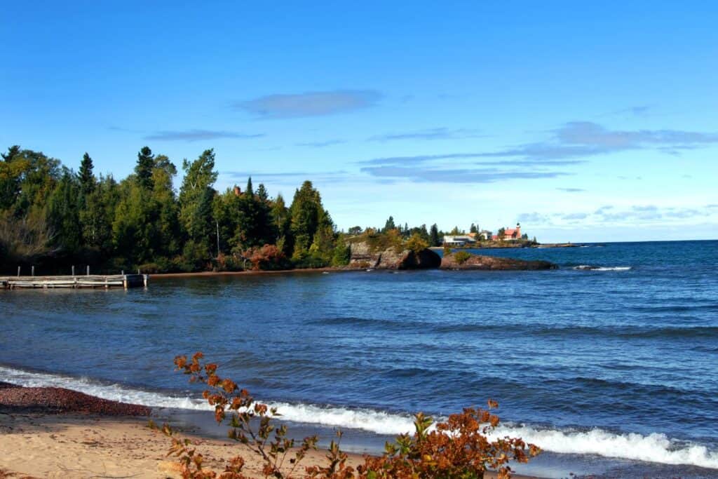 Lake Superior shoreline on the Keweenaw Peninsula in Michigan’s Upper Peninsula with rocky coast, trees, and a distant lighthouse