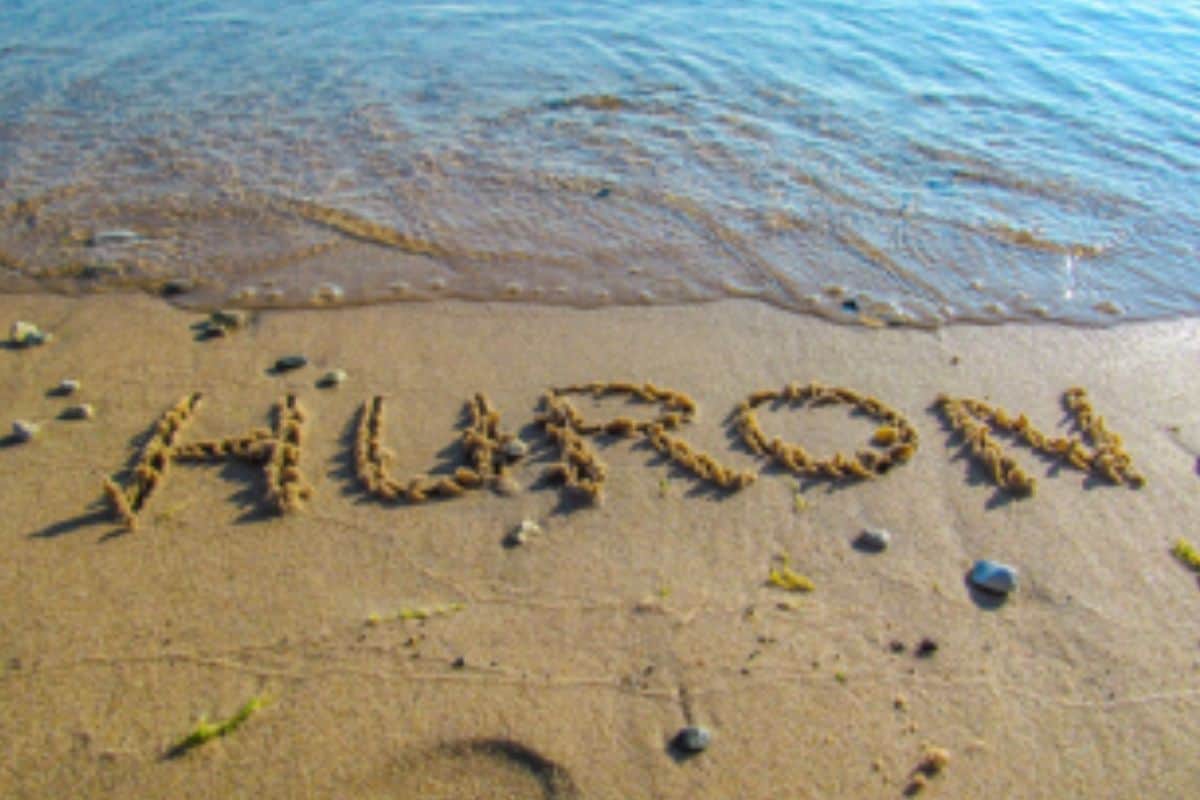 Lake Huron shoreline with word Huron written in sand at water’s edge
