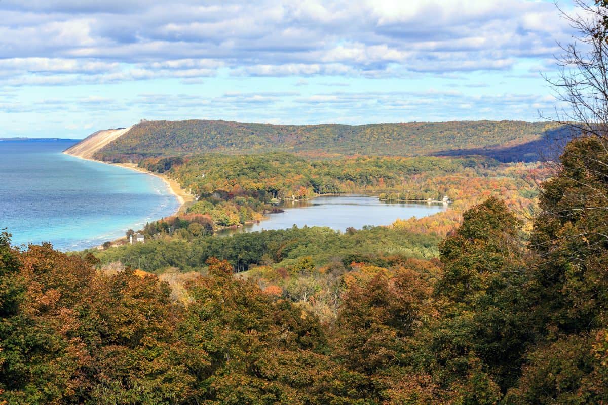 Aerial view of Sleeping Bear Dunes National Lakeshore in fall showing Lake Michigan shoreline, inland lake, and autumn foliage from the overlook