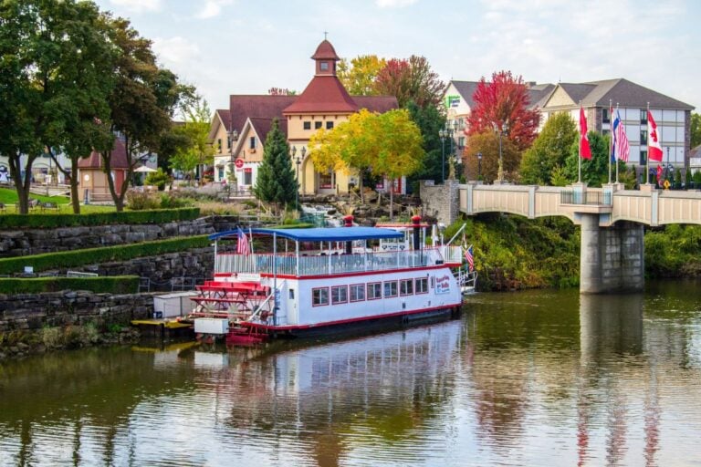 The Bavarian Belle paddlewheel riverboat docked on the Cass River below River Place Shops in Frankenmuth, Michigan, with fall color along the bank
