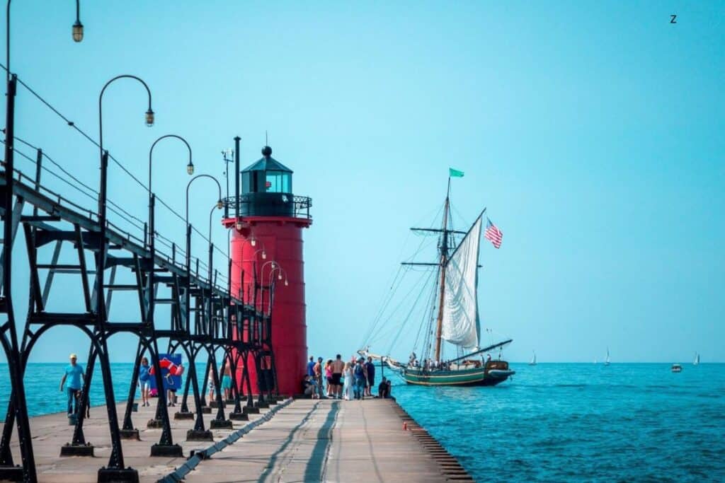 pier with red lighthouse at end and boat in background