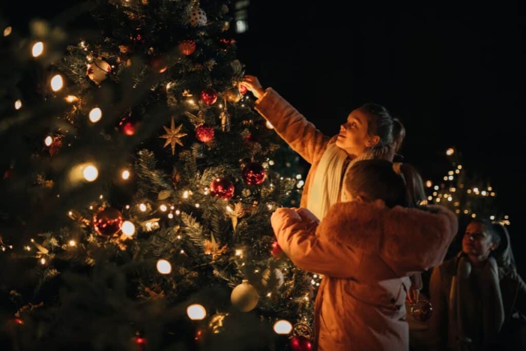 people hanging ornaments on a christmas tree in detroit