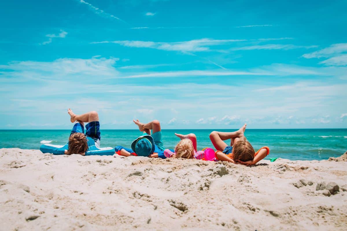 kids lying on a beach with a blue sky in the background