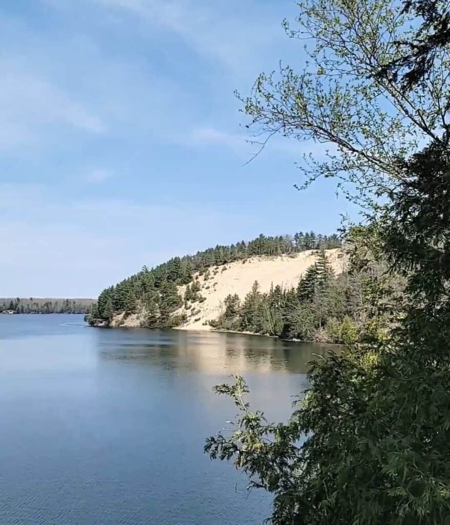 View of the AuSable River and a large sand dune across the water from the dune observation deck near Lumberman's Monument in Oscoda, Michigan