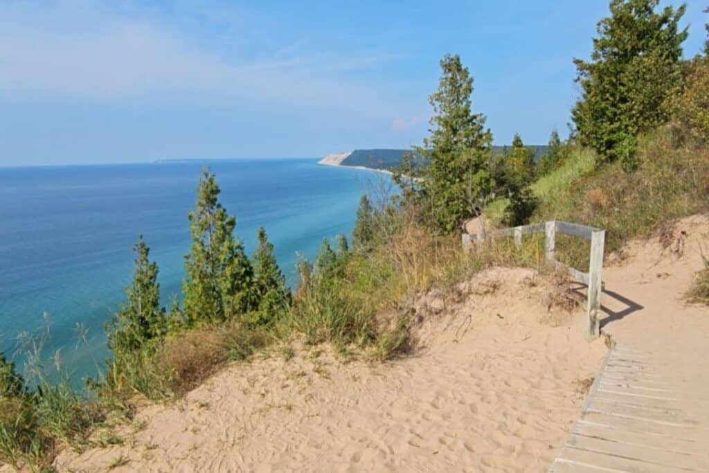 Wooden boardwalk railing along Empire Bluff Trail overlooking turquoise Lake Michigan and Sleeping Bear Dunes shoreline
