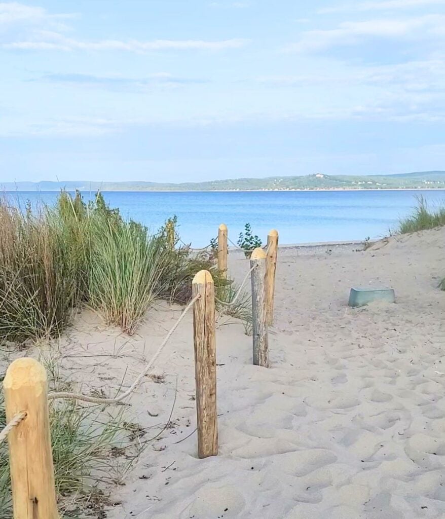Sandy beach path with rope-and-post fencing leading to Sleeping Bear Bay near Glen Haven