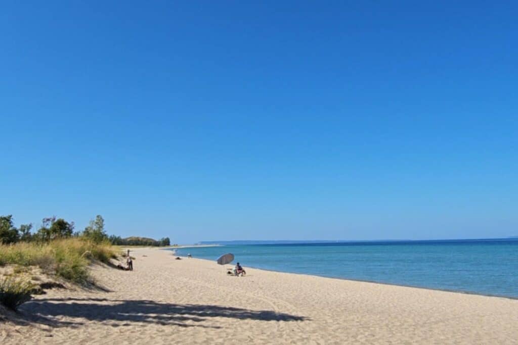 Wide sandy Glen Haven Beach on Sleeping Bear Bay with calm Lake Michigan water and visitors