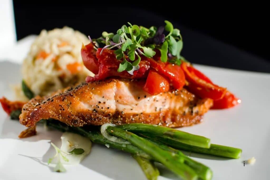 Pan-seared salmon with roasted red peppers, microgreens, asparagus, and risotto at RyeBelles in St. Joseph Michigan