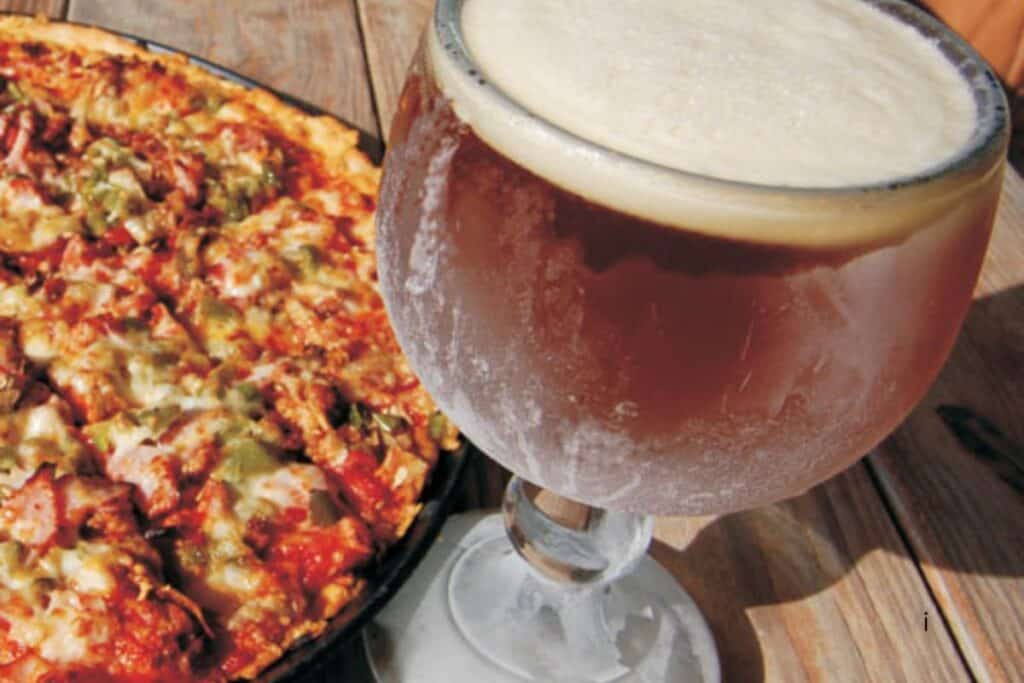 Supreme pizza and a goblet of craft beer on a wood table at a St. Joseph Michigan restaurant