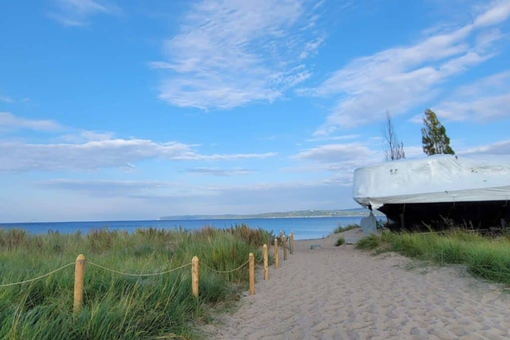 Beach path near the Sleeping Bear Point Maritime Museum with a winterized historic boat on the right