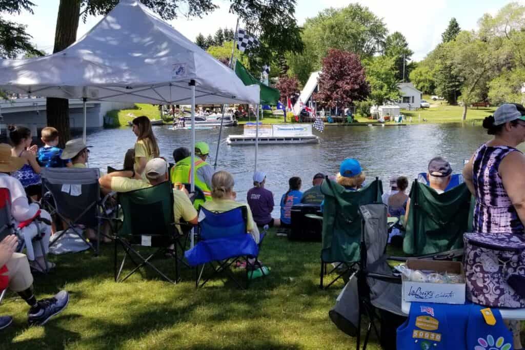 Crowd in lawn chairs watching the AuSable River Canoe Marathon along the river bank in Oscoda Michigan