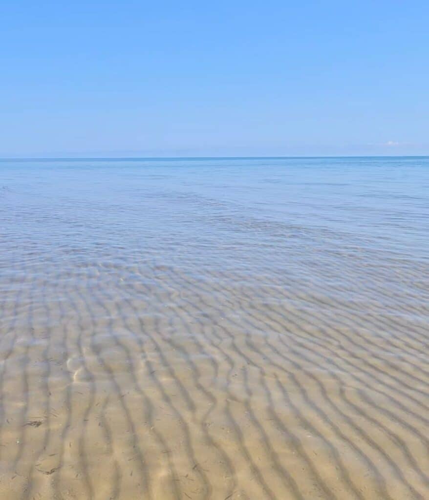 Crystal clear shallow water with rippled sand at Oscoda Beach Park on Lake Huron