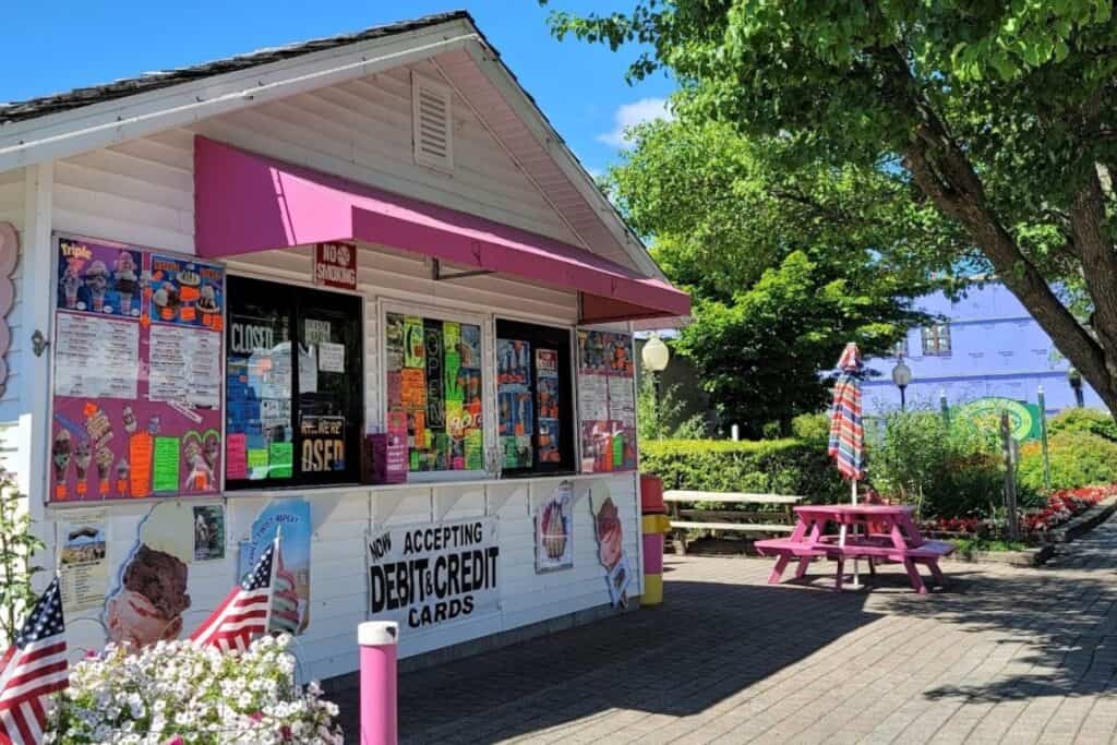 Pink and white Parkside Dairy ice cream shop with menu boards and pink picnic table in downtown Oscoda Michigan