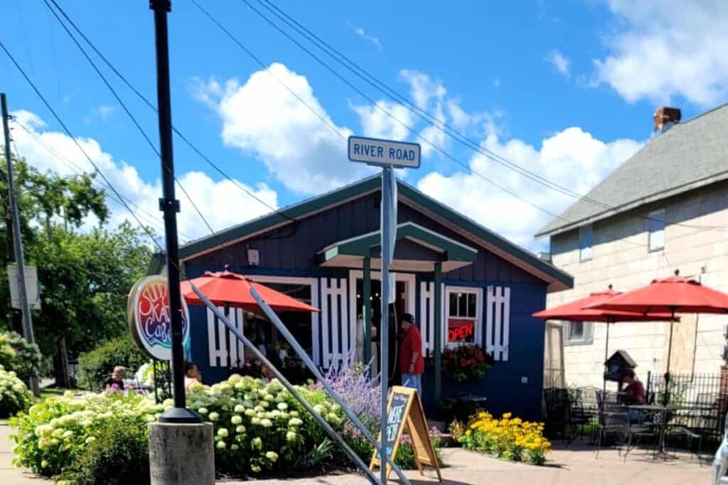 Sunrise Kava Cafe blue building with red umbrellas and outdoor seating on River Road in Oscoda Michigan