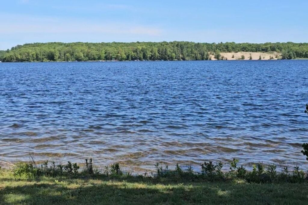 Wide Au Sable River dam pond with a sand dune on the far shore near Oscoda, Michigan