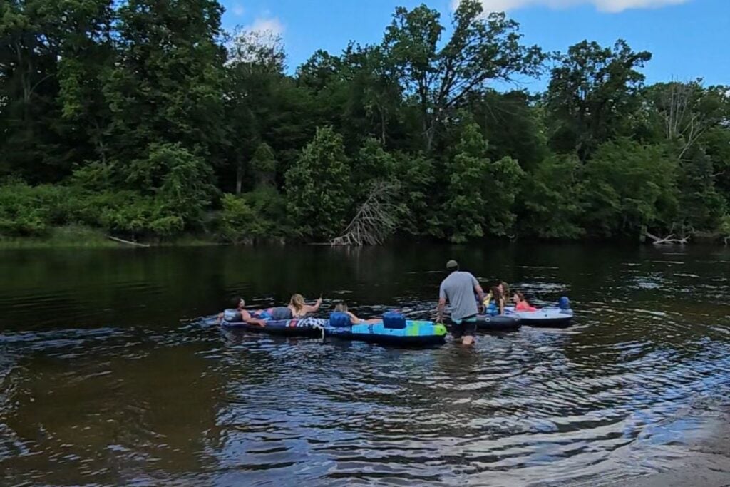 Group of people tubing and floating together on the calm Au Sable River near Oscoda, Michigan