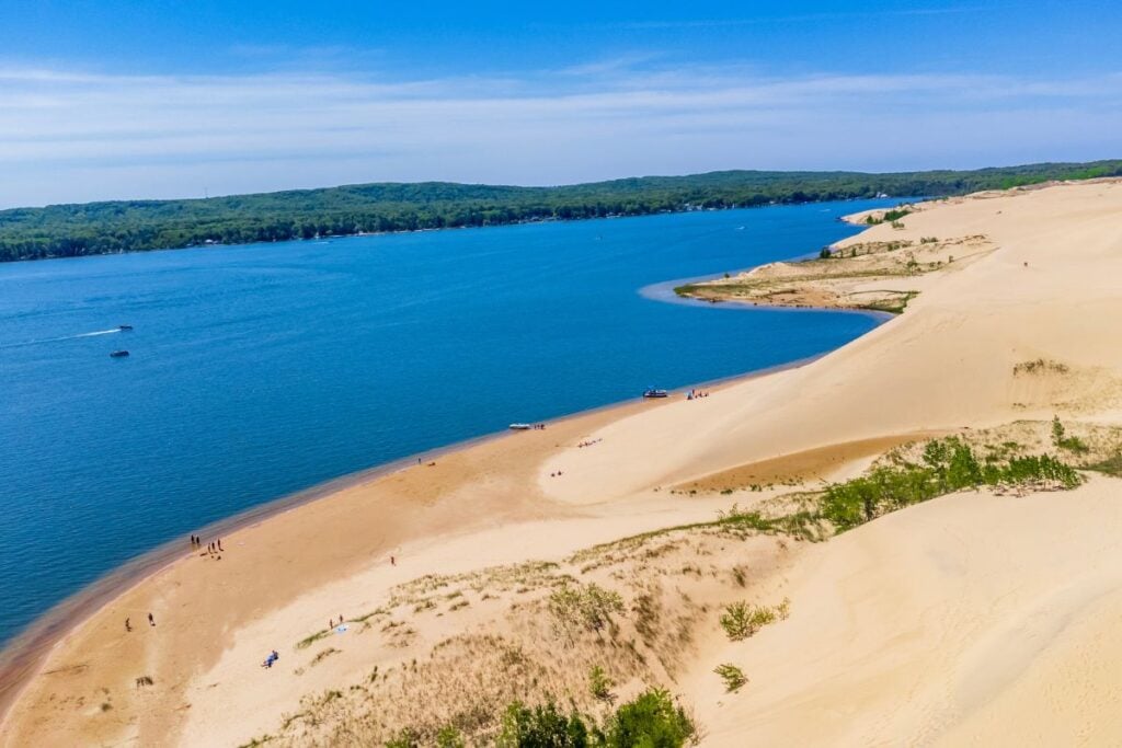 Aerial view of the sand dunes at Silver Lake in Mears, Michigan, sloping down to a sandy beach with boats on the water
