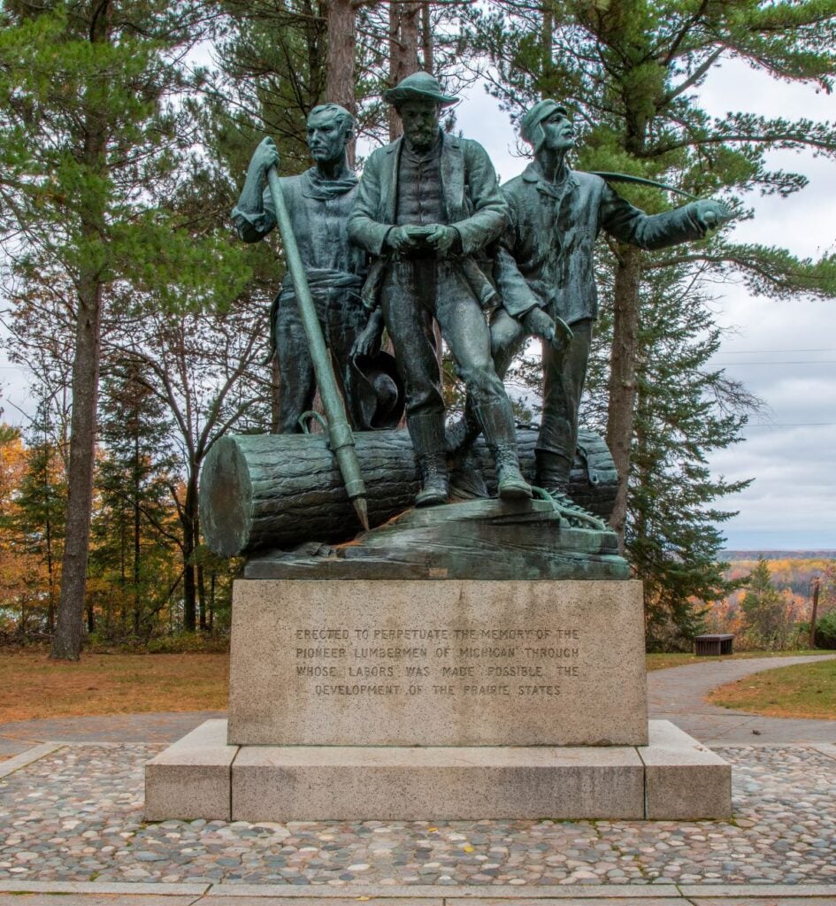 Bronze Lumberman's Monument statue of three loggers with a log, on a granite base near Oscoda, Michigan